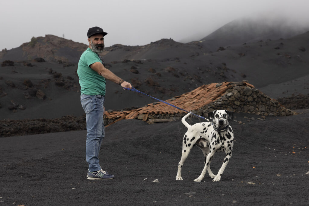 The father, Moises Ramos Leon, (48) with his dog, Franco. A family play and relax on what was a vineyard. They lost everything in the eruptions. West Las Manchas. 

La Palma. An island of the Canaries. Two years after the Cumbre Vieja volcanic eruption in late 2021.  Photography taken on January 2024.