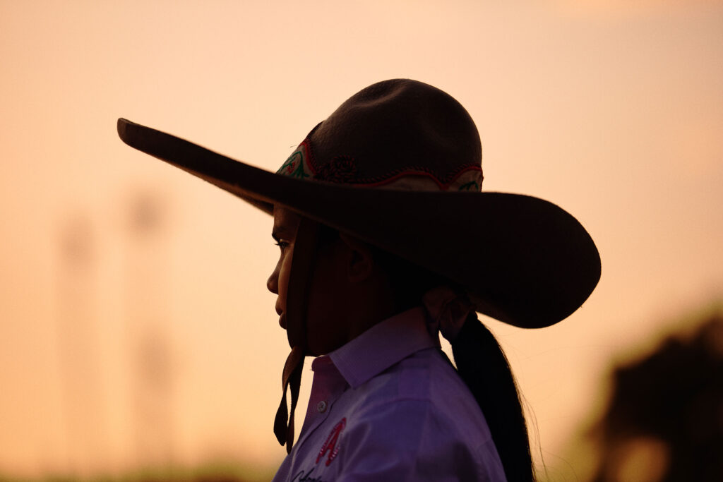 © Owen Harvey - Julissa sits on her horse at the end of rehearsals, silhouetted by the evening sun. Jurupa Vallery. 2024.